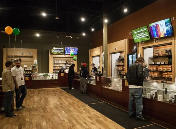 A dispensary sales floor with customers at the display counters.